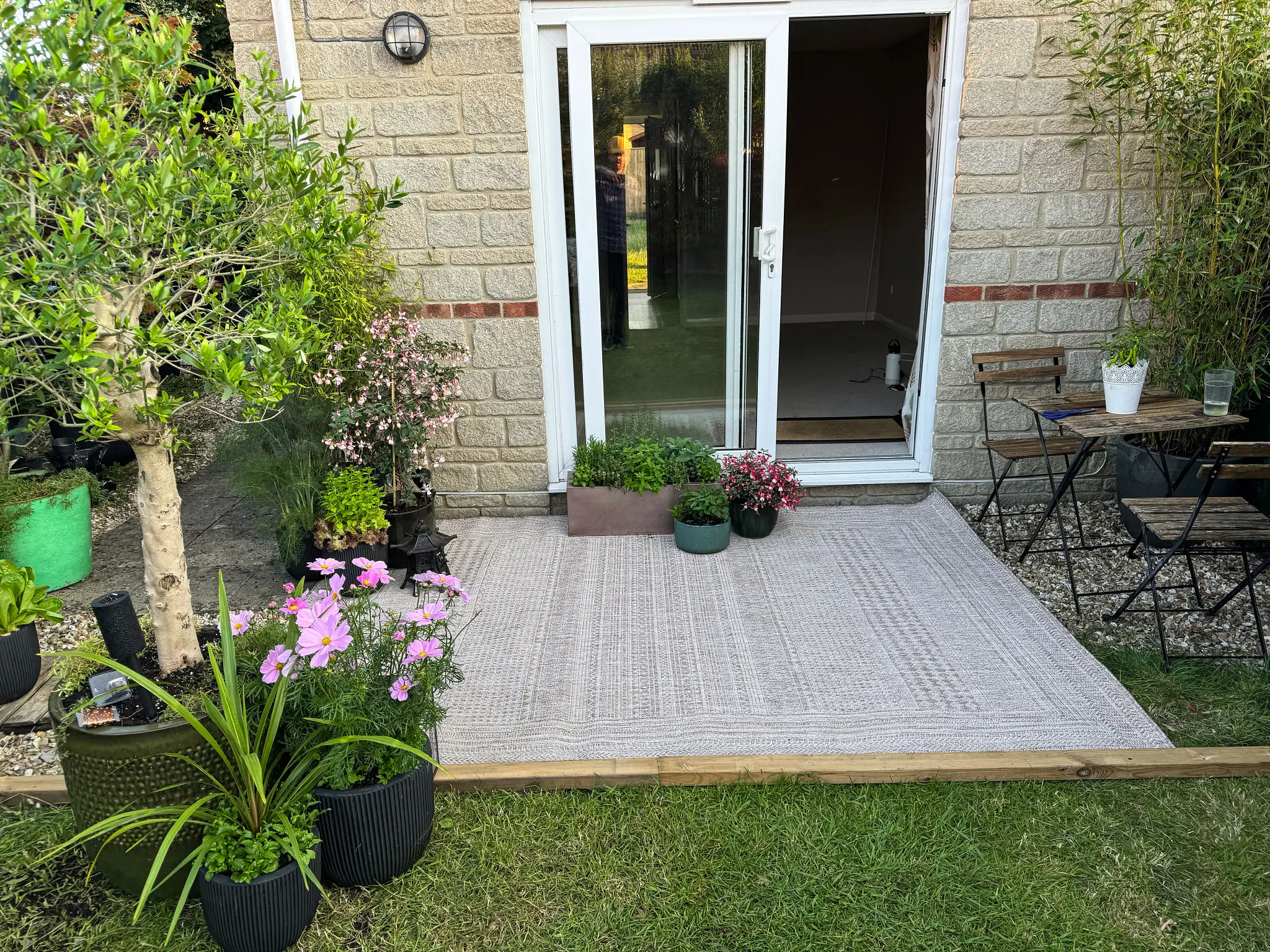 Small patio with potted plants outside a sliding glass door.