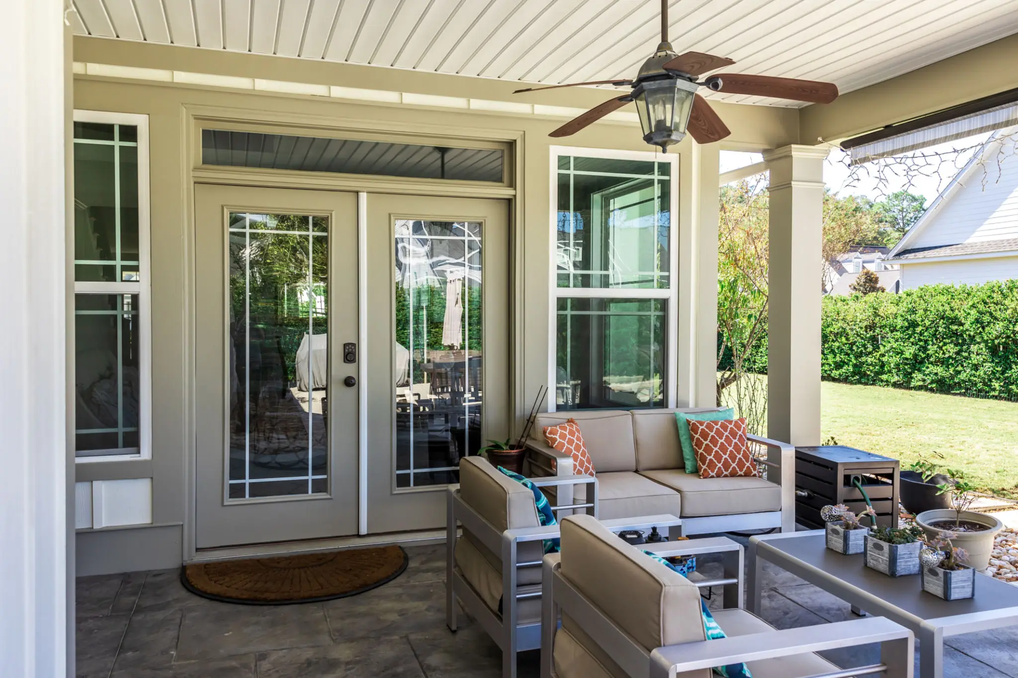 Cozy outdoor seating area with cushioned chairs and a ceiling fan.